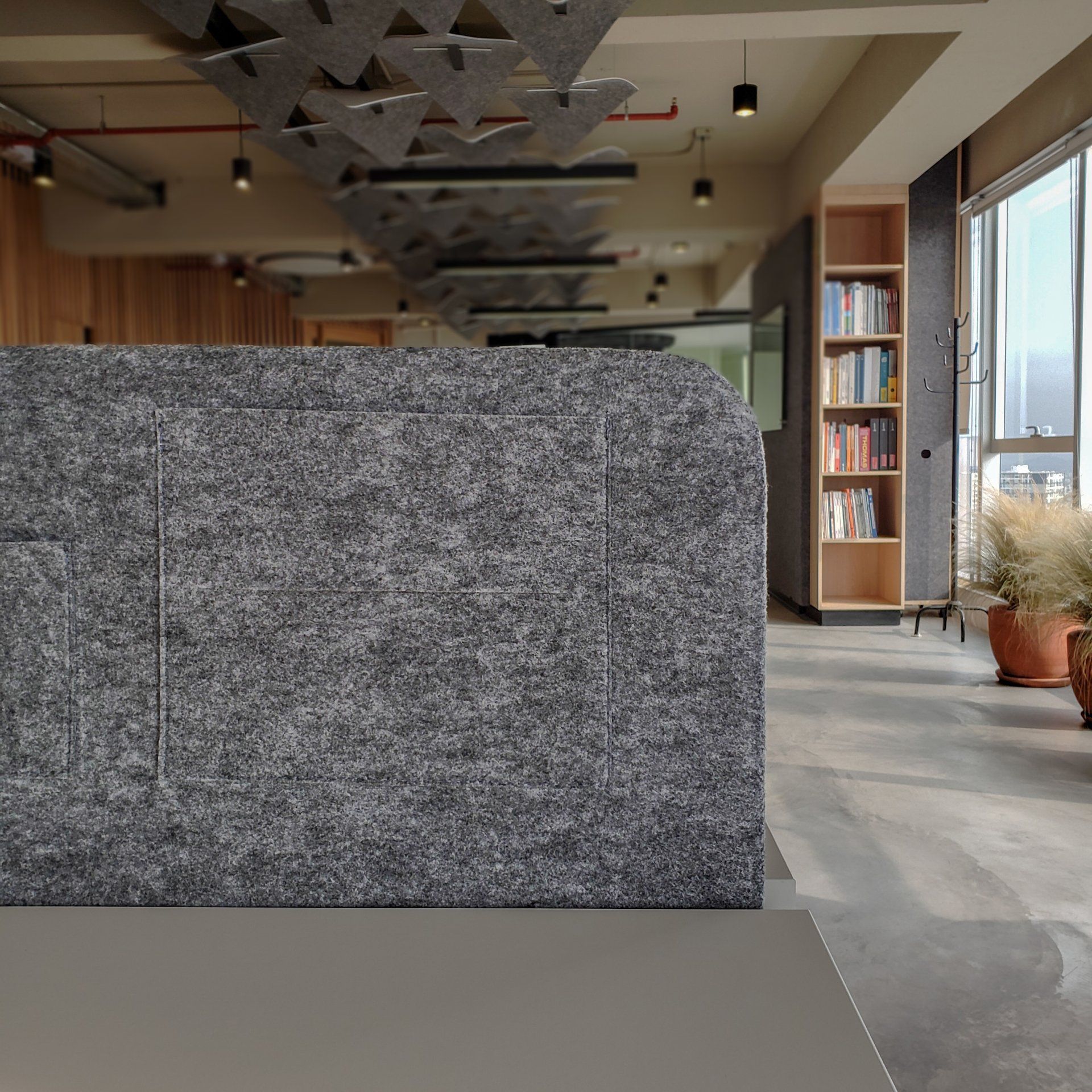 Una pared gris en una habitación con una estantería al fondo.