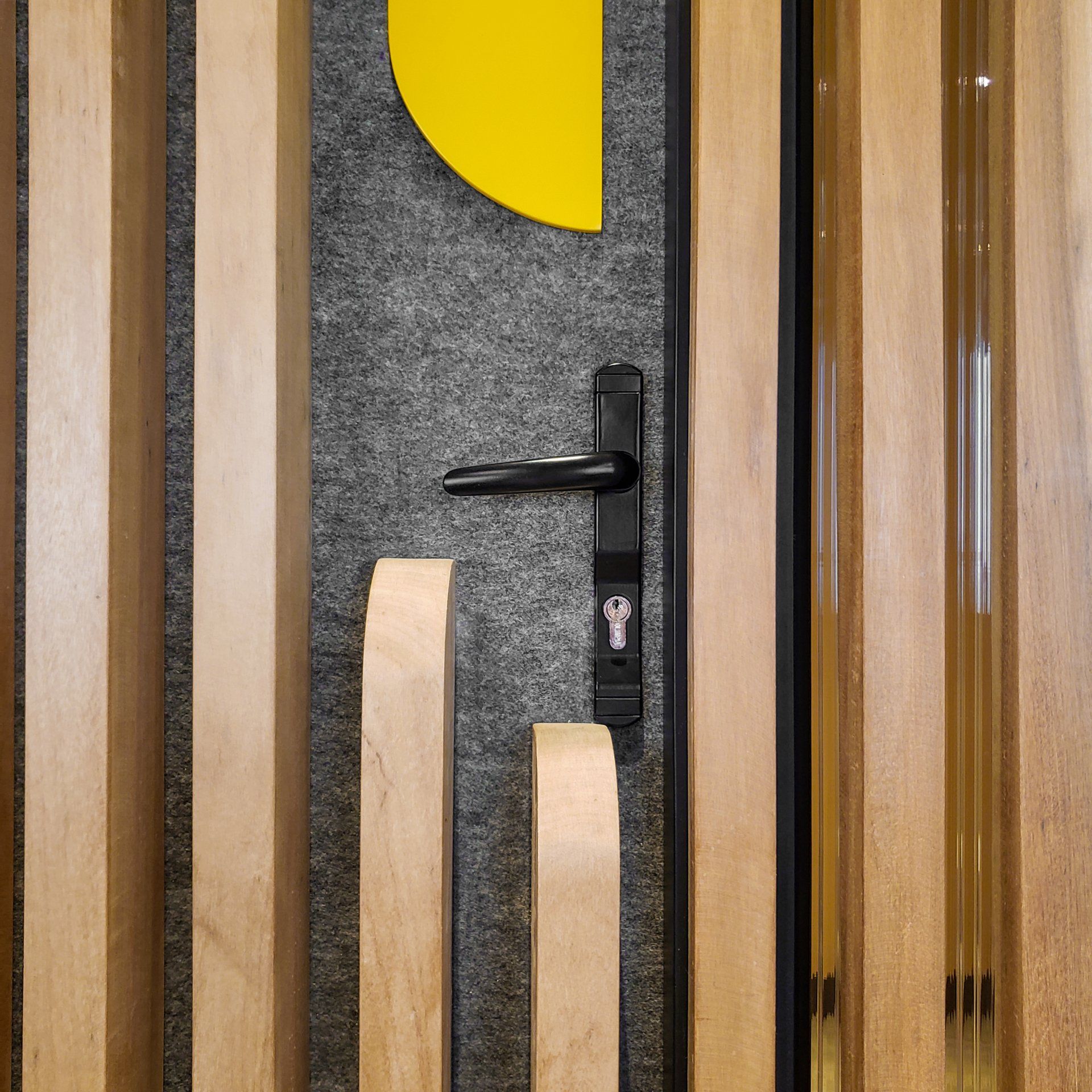 Una puerta de madera con un tirador negro y un círculo amarillo en la pared detrás de ella.