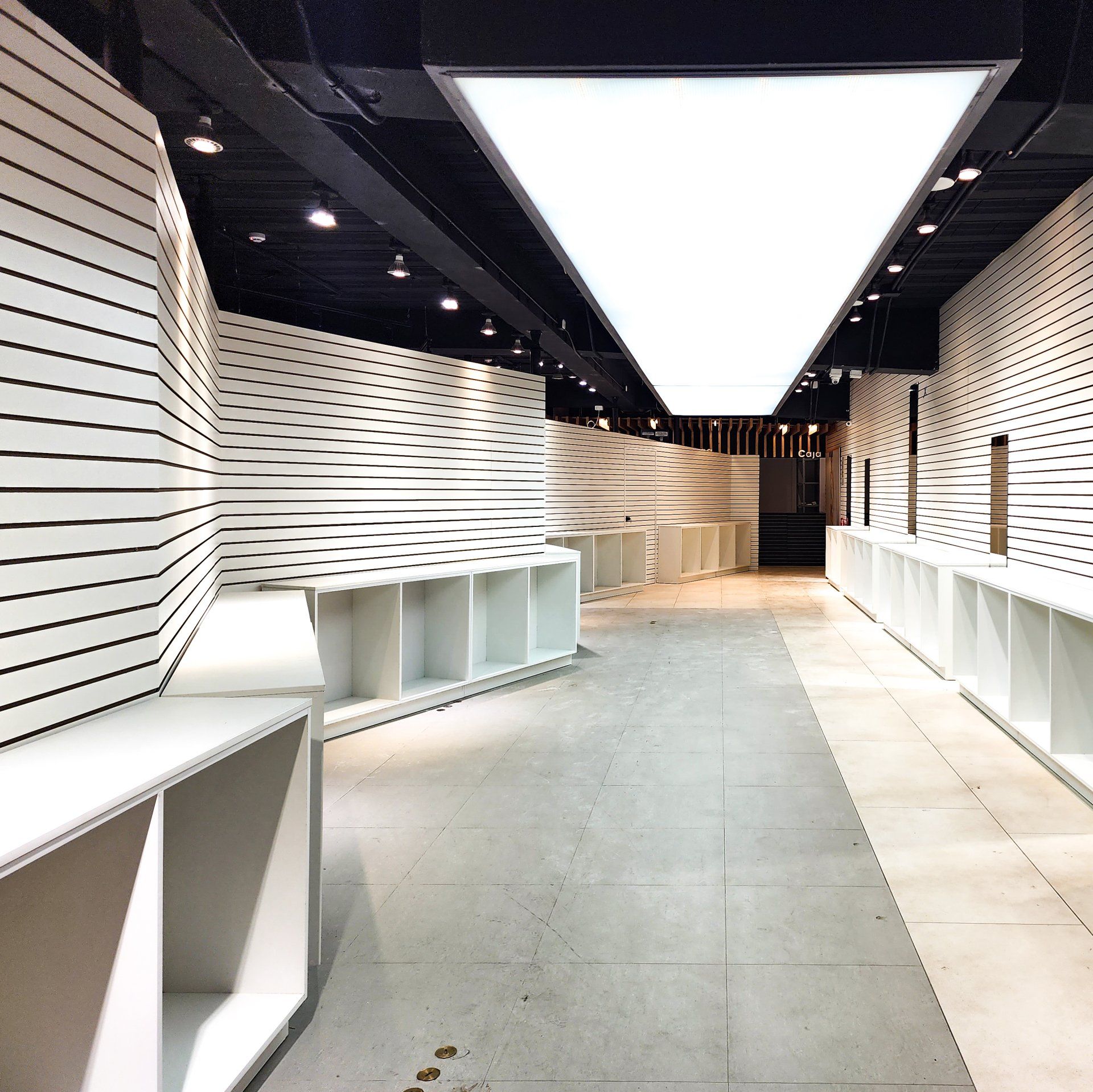 Un largo pasillo con estantes blancos y un techo blanco.