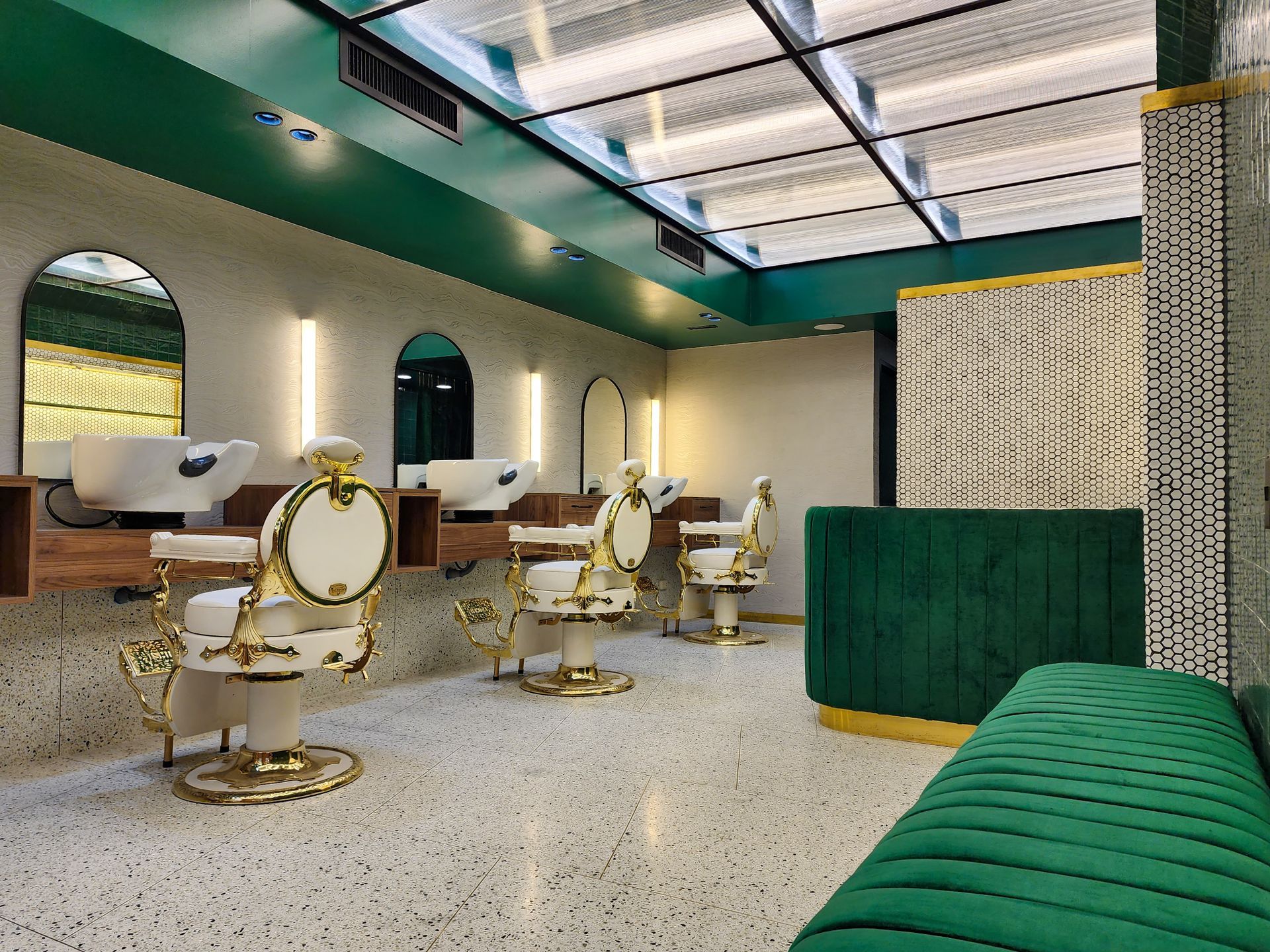 Una barbería con un banco verde y sillas de barbero.