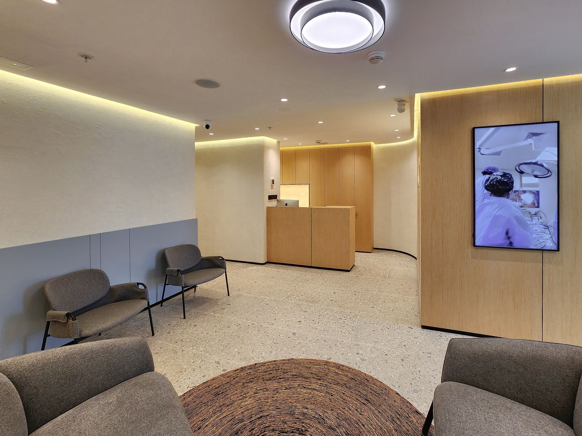 Una sala de espera con sillas y un televisor en la pared.