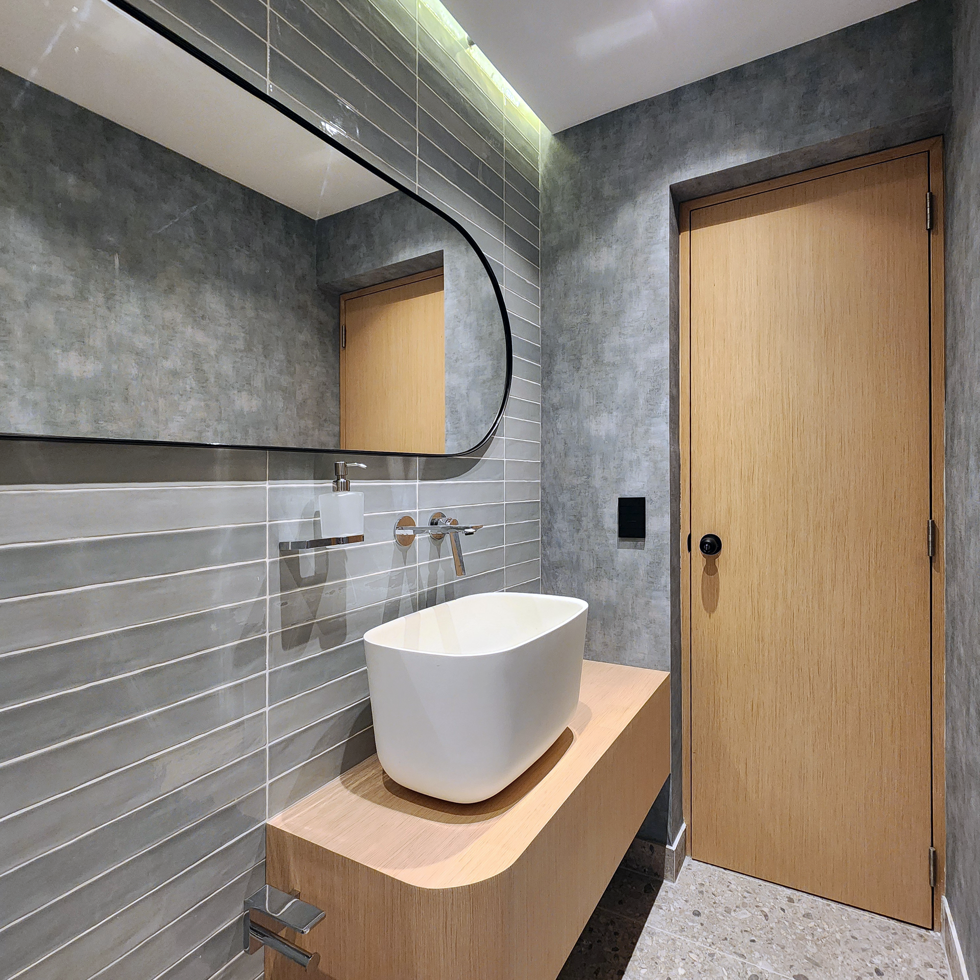 Un baño con lavabo, espejo y puerta de madera.