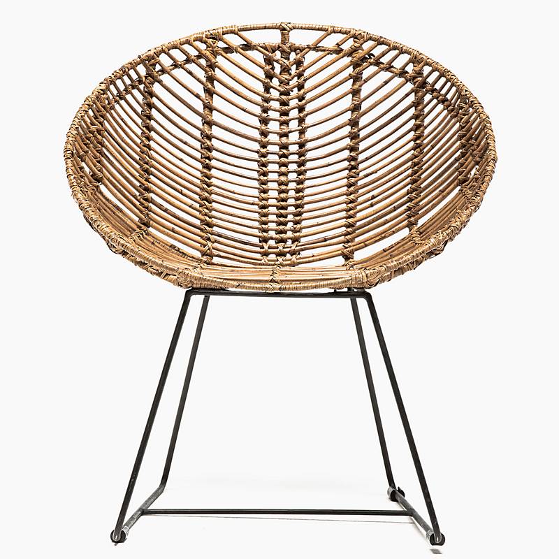 Una silla de mimbre con estructura de metal negro sobre fondo blanco.