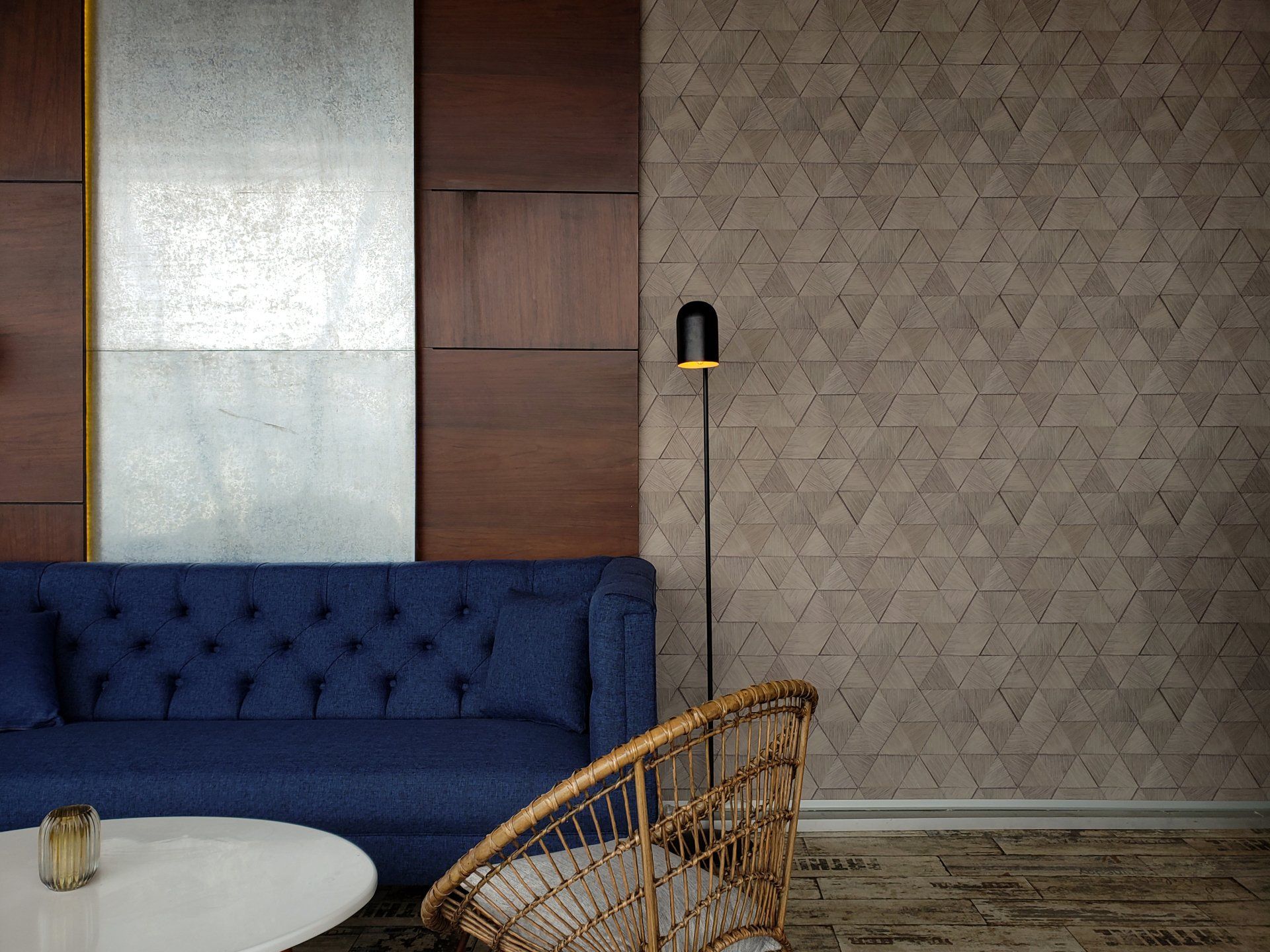 Una sala de estar con un sofá azul, una silla de mimbre, una mesa y una lámpara.