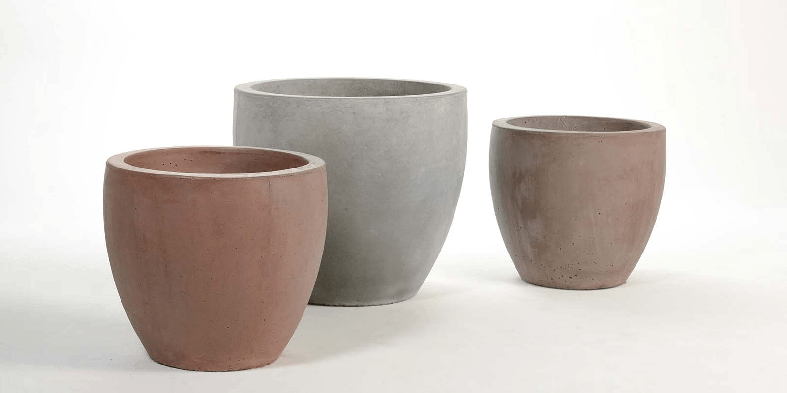 Tres ollas de barro están colocadas una al lado de la otra sobre una superficie blanca.