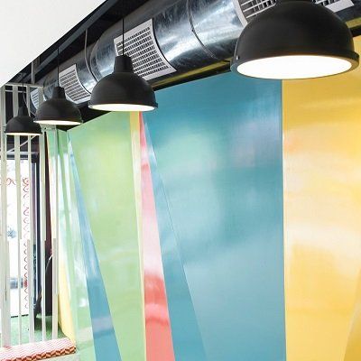 Una hilera de lámparas colgando del techo frente a una pared colorida.