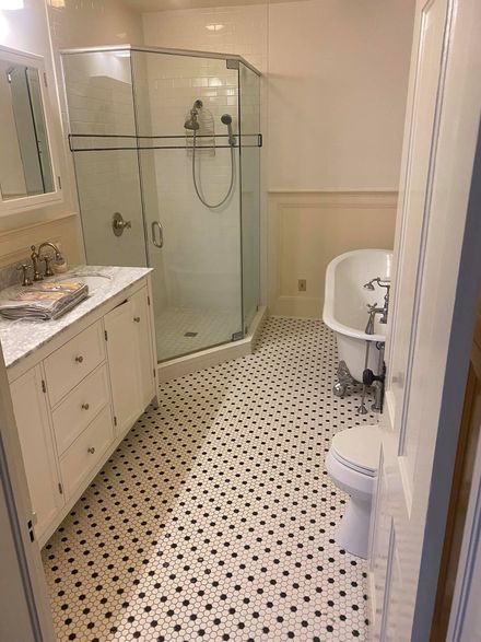 Bathroom with white vanity, corner shower, clawfoot tub, and black and white patterned floor tiles.