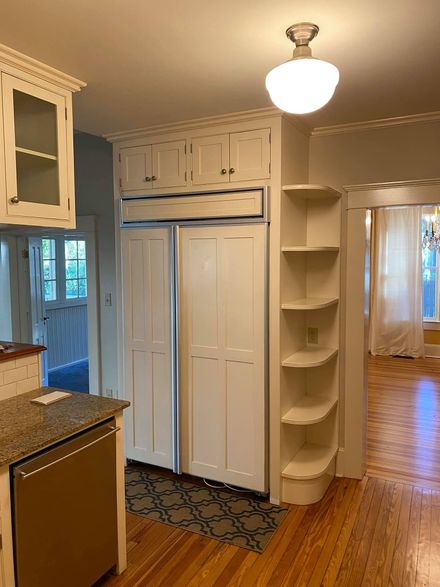 Kitchen with white cabinetry, a built-in refrigerator, open shelving, and hardwood floors.