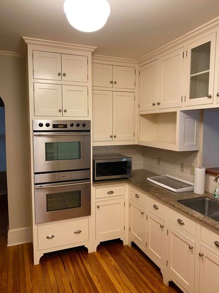 Cream-colored kitchen cabinets with stainless steel double oven, microwave, and granite countertops.