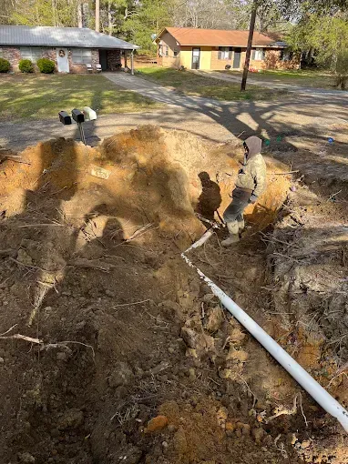 A man is digging a hole in the dirt in front of a house.