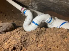 A white pipe is laying in the dirt.