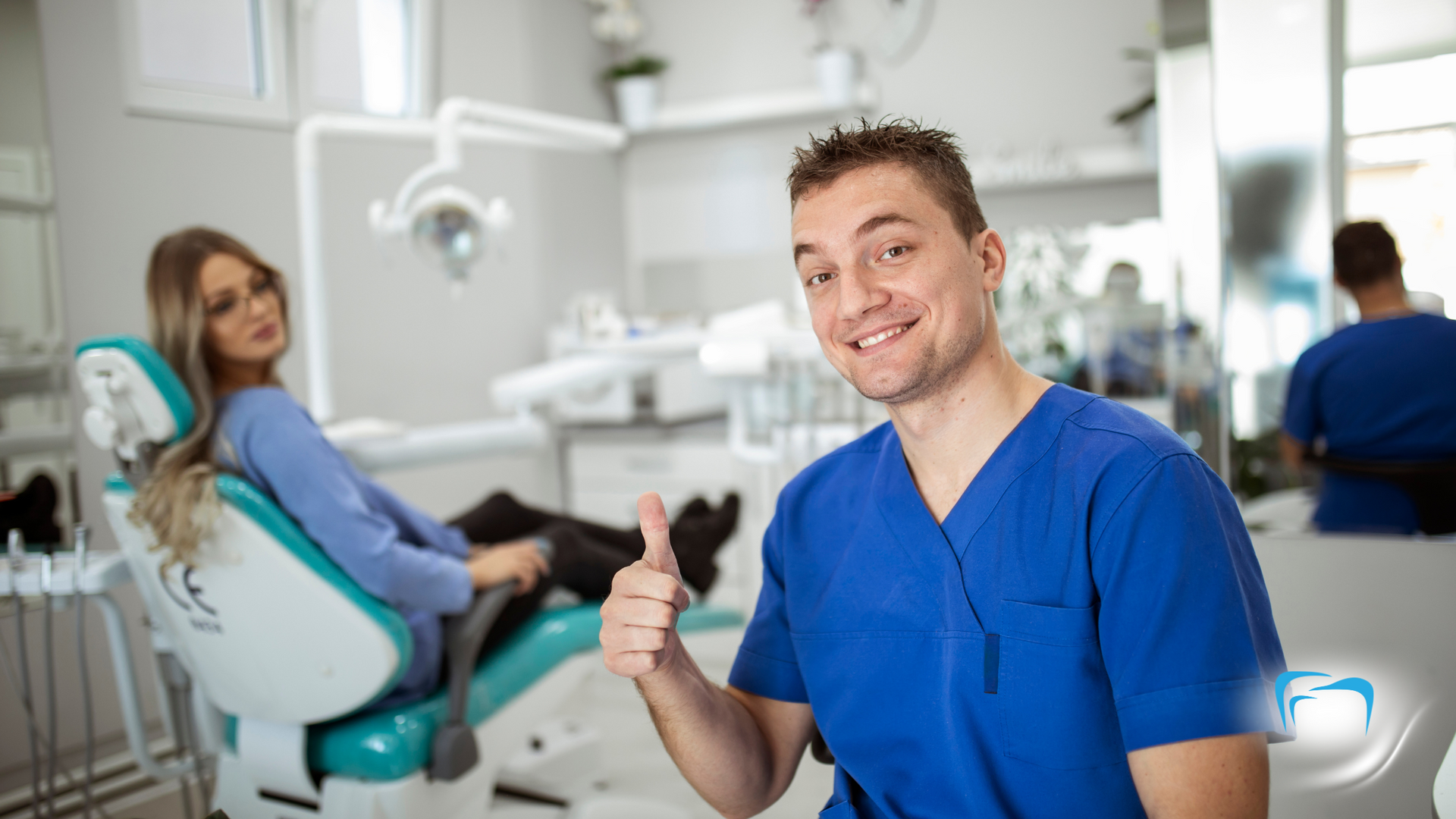 A dentist is giving a thumbs up to a patient in a dental chair.
