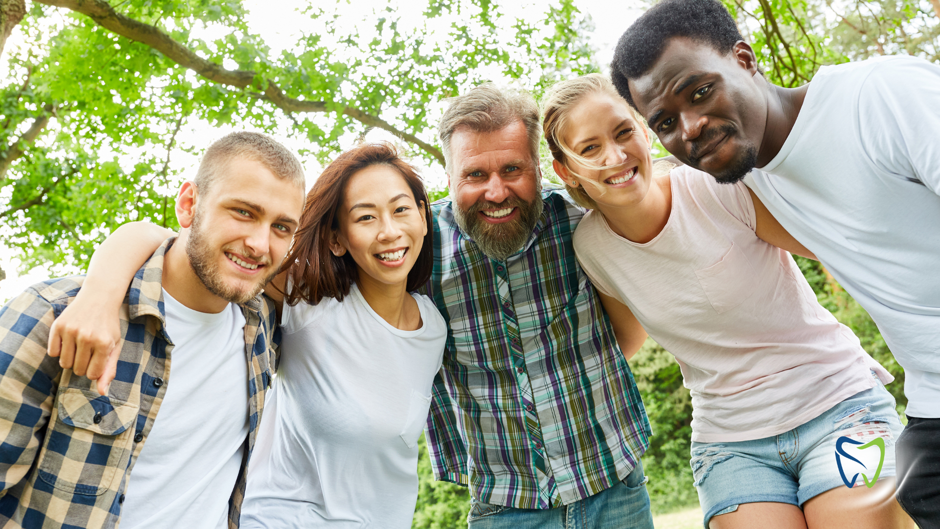 A group of young people are posing for a picture together in a park.