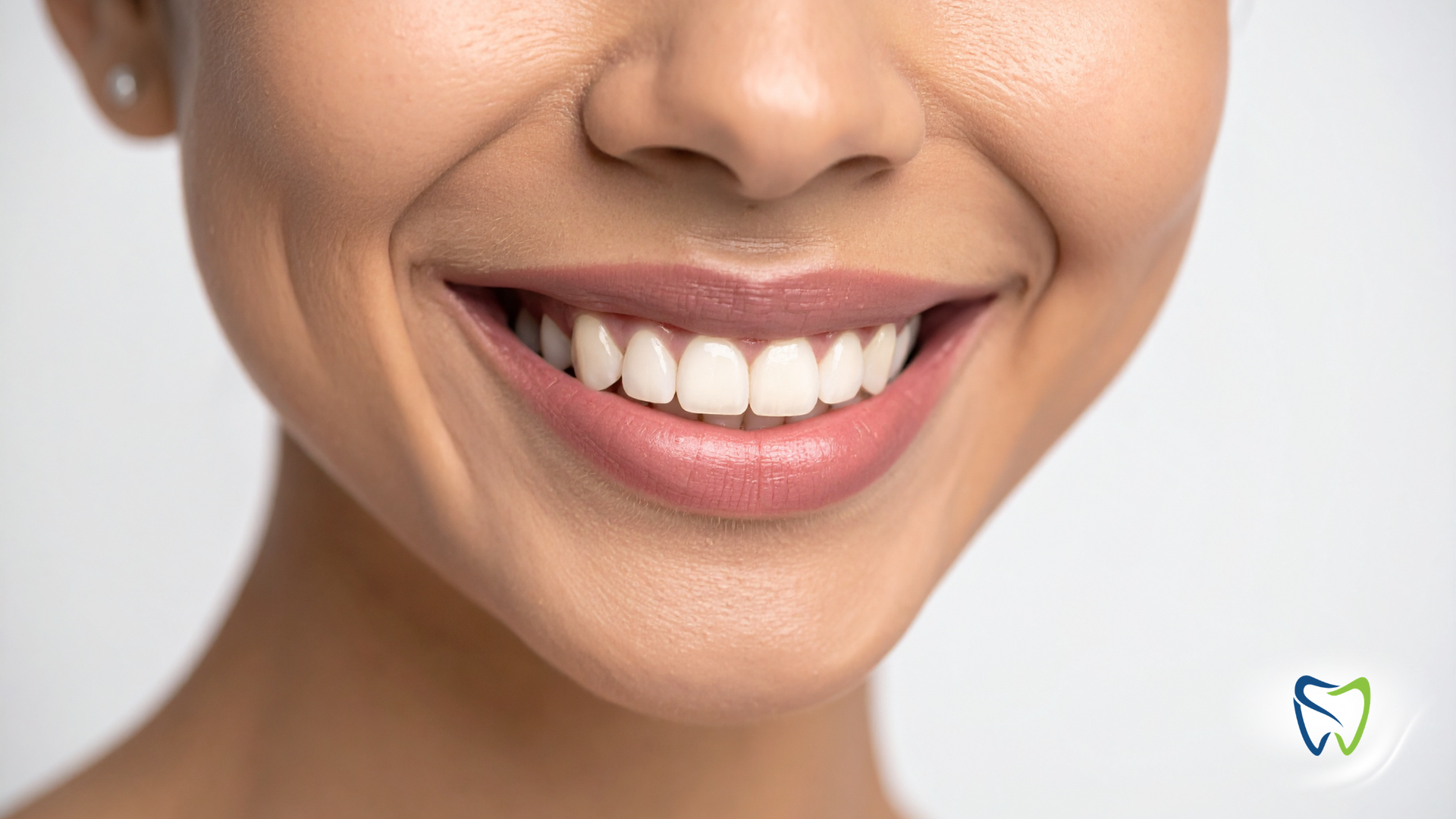 Close-up of a person's mouth, showing slightly discolored teeth and a mole on the chin.