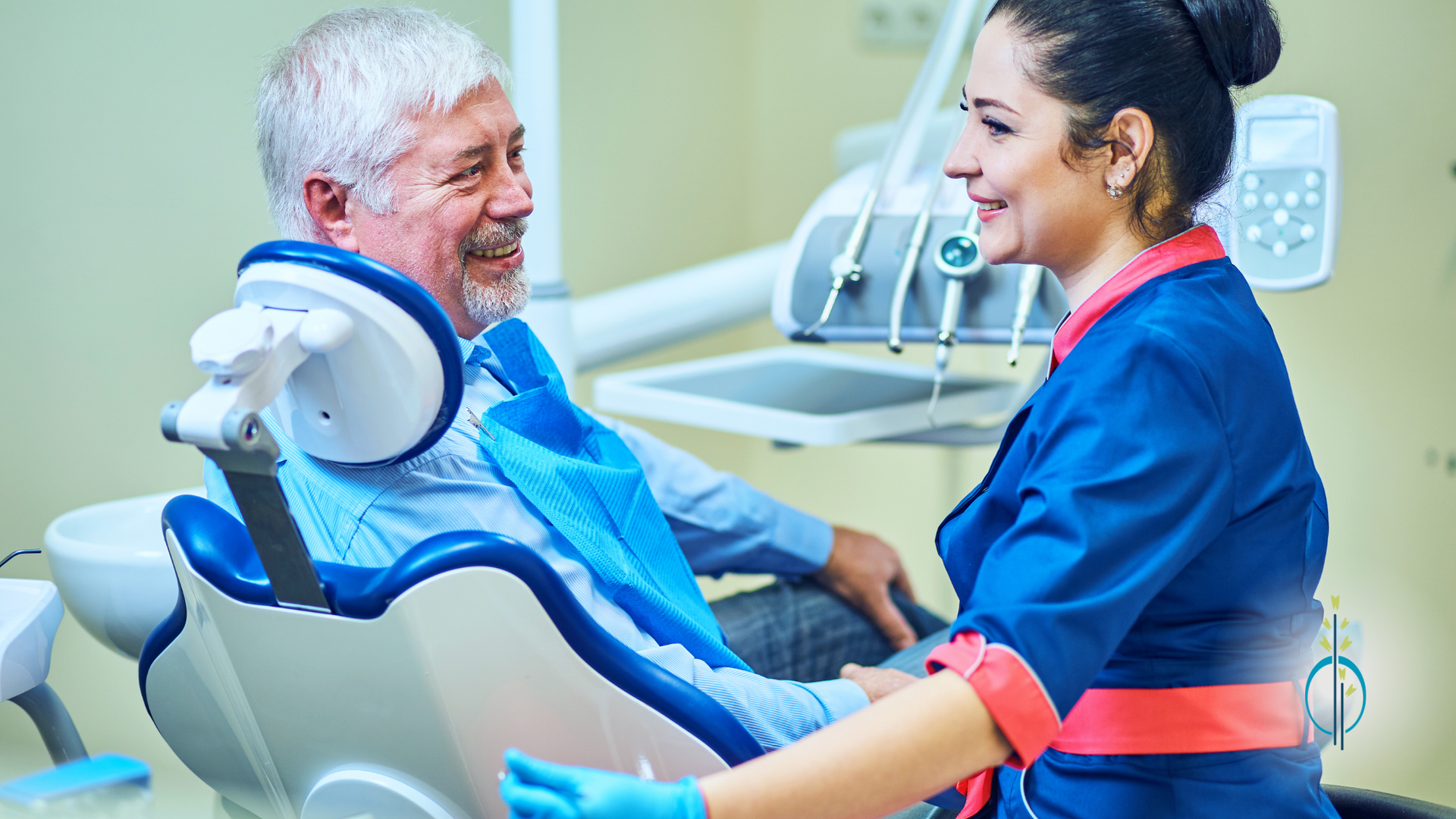 An older man is sitting in a dental chair talking to a female dentist.