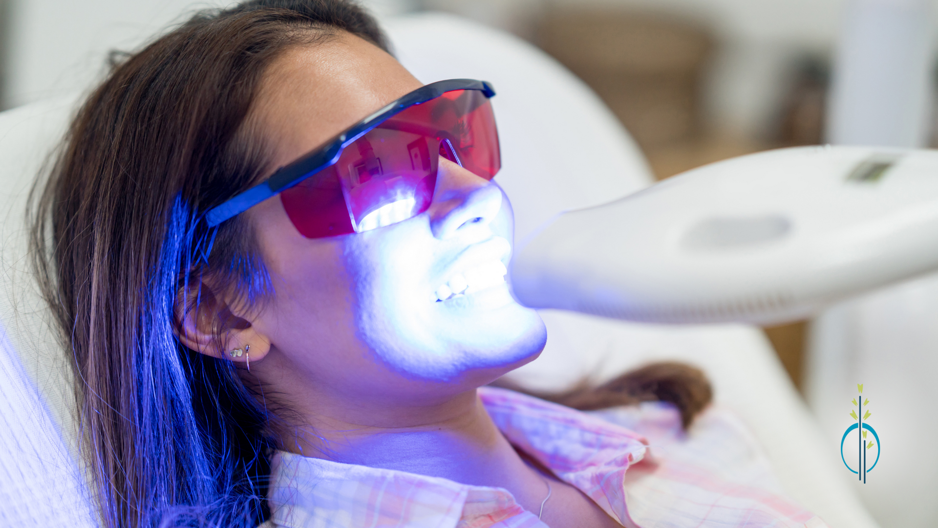 A woman is getting a teeth whitening treatment in a dental office.