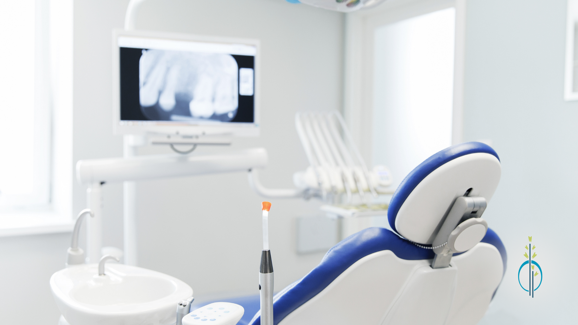 A dental office with a dental chair , sink , and monitor.