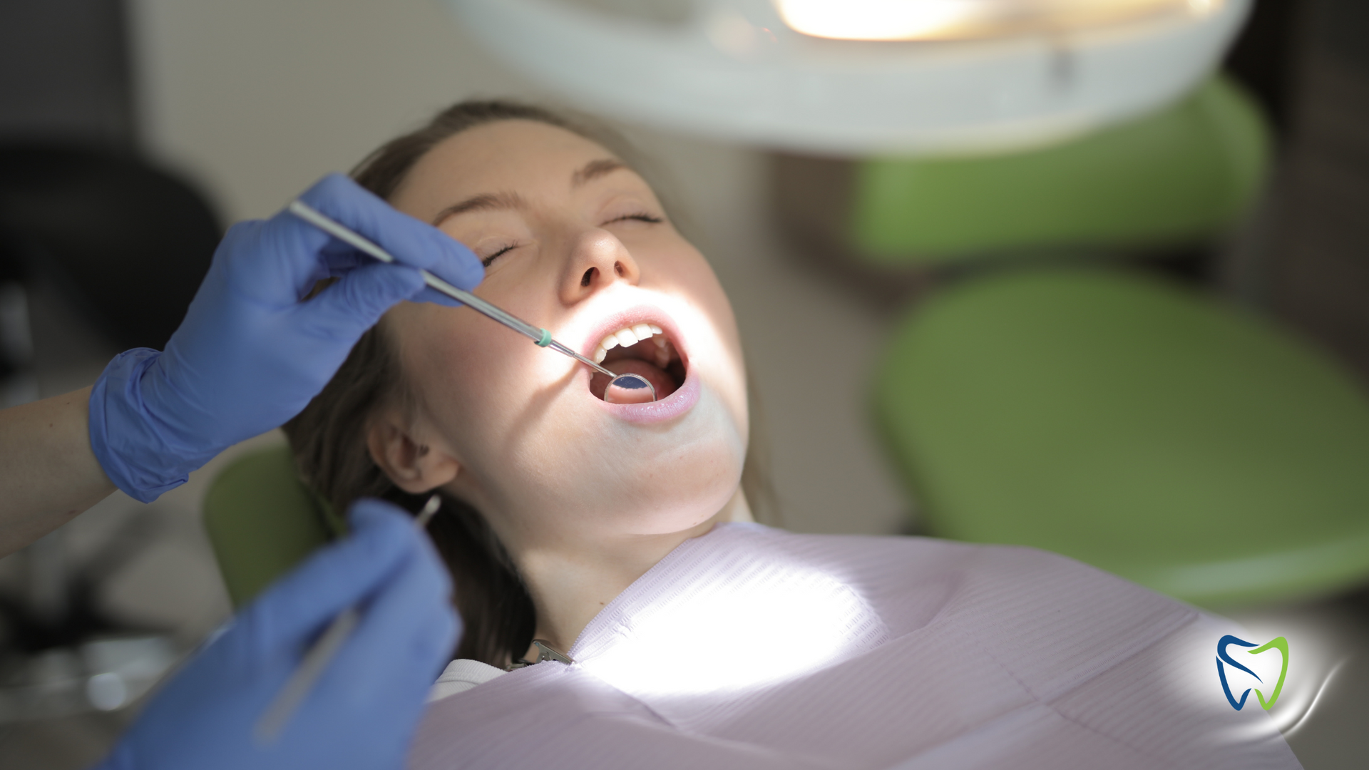 A woman is getting her teeth examined by a dentist in a dental chair.