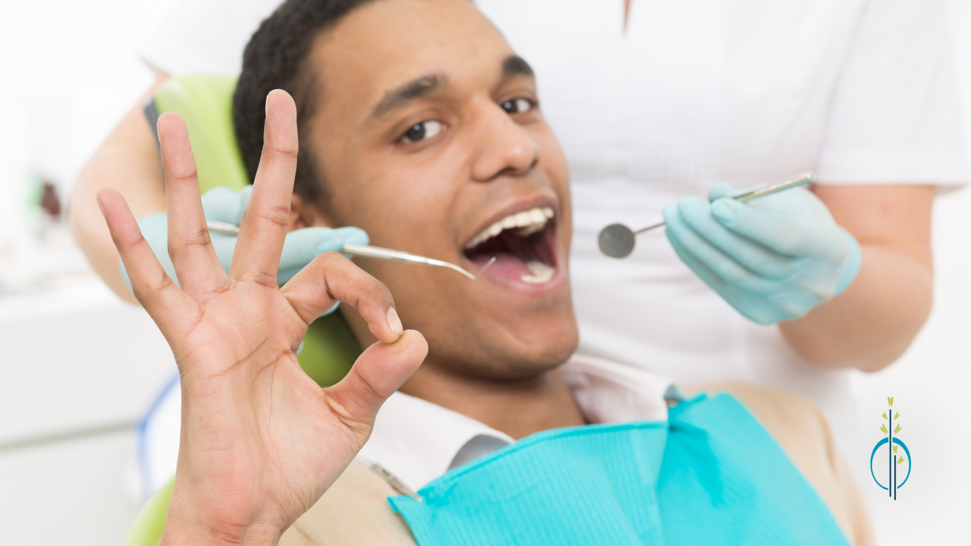 A man is sitting in a dental chair giving an okay sign.