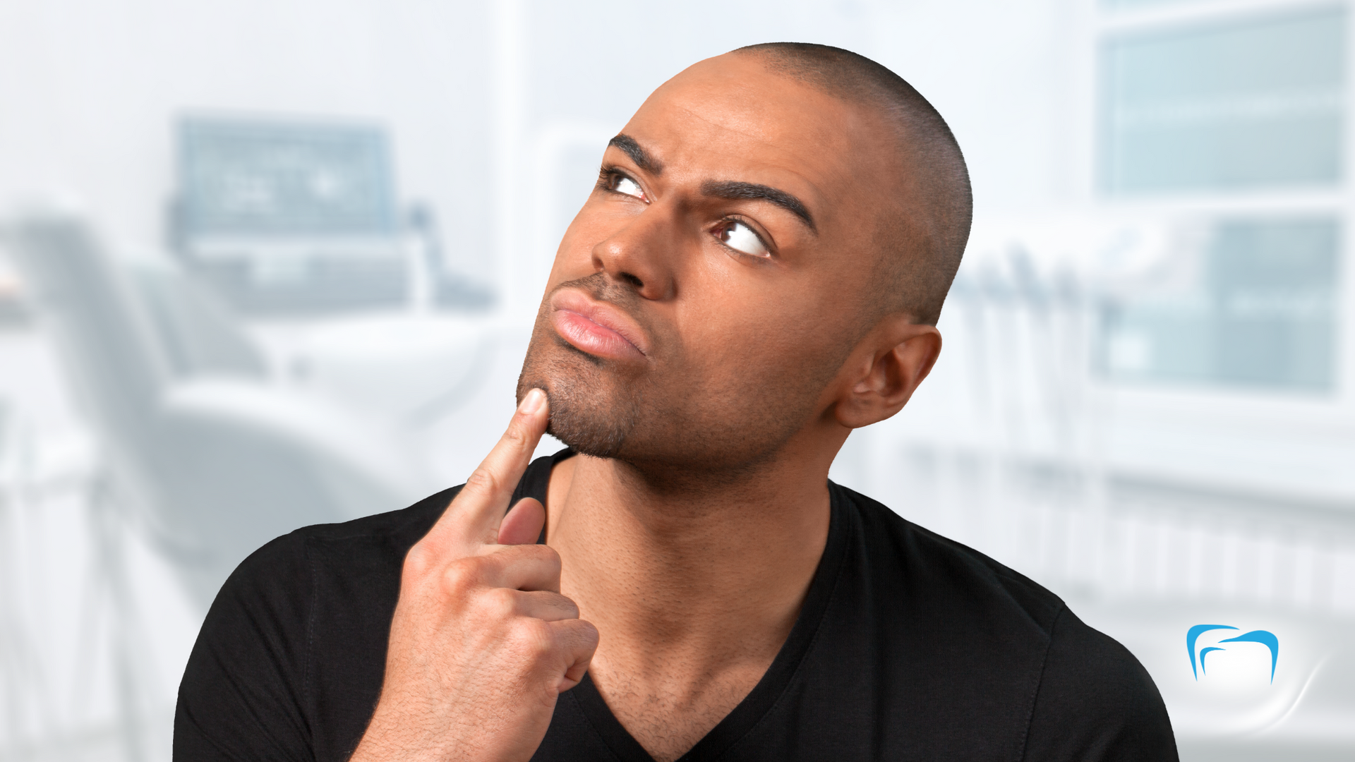 A man in a black shirt is thinking with his finger on his chin.
