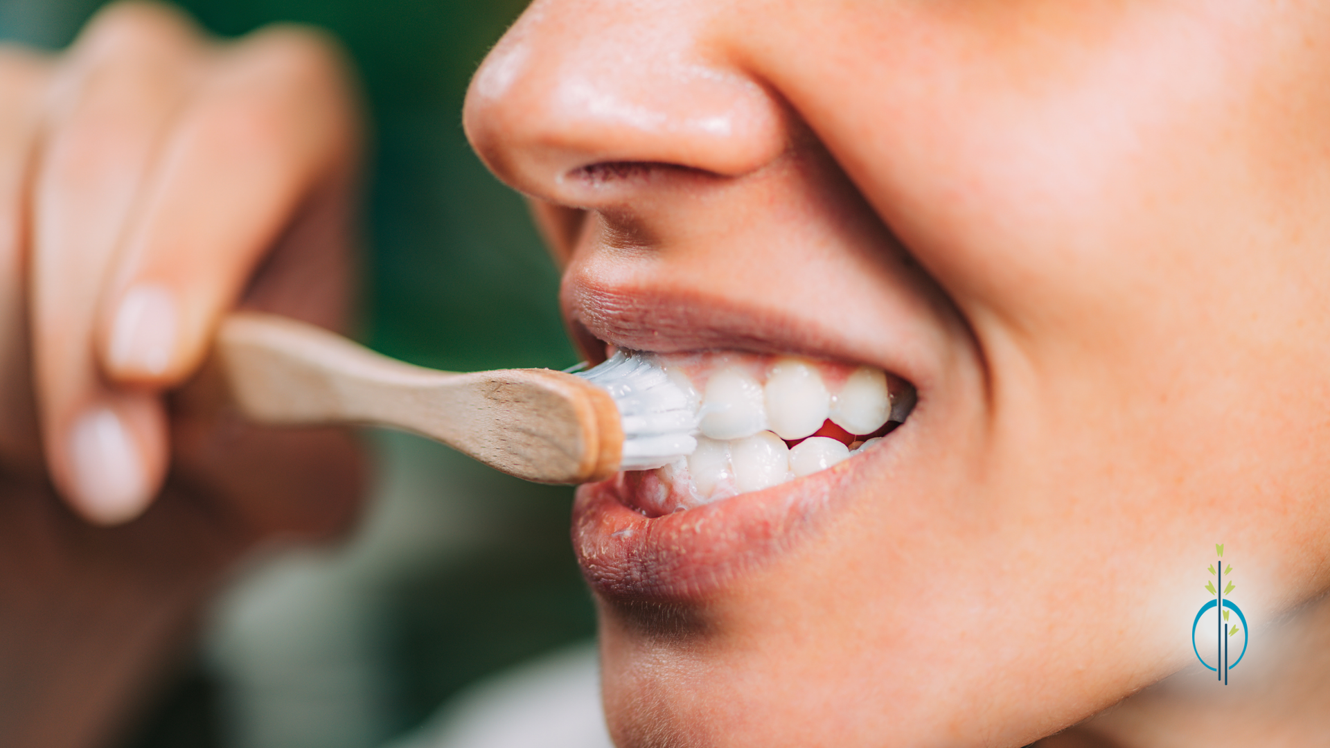 A woman is brushing her teeth with a wooden toothbrush.