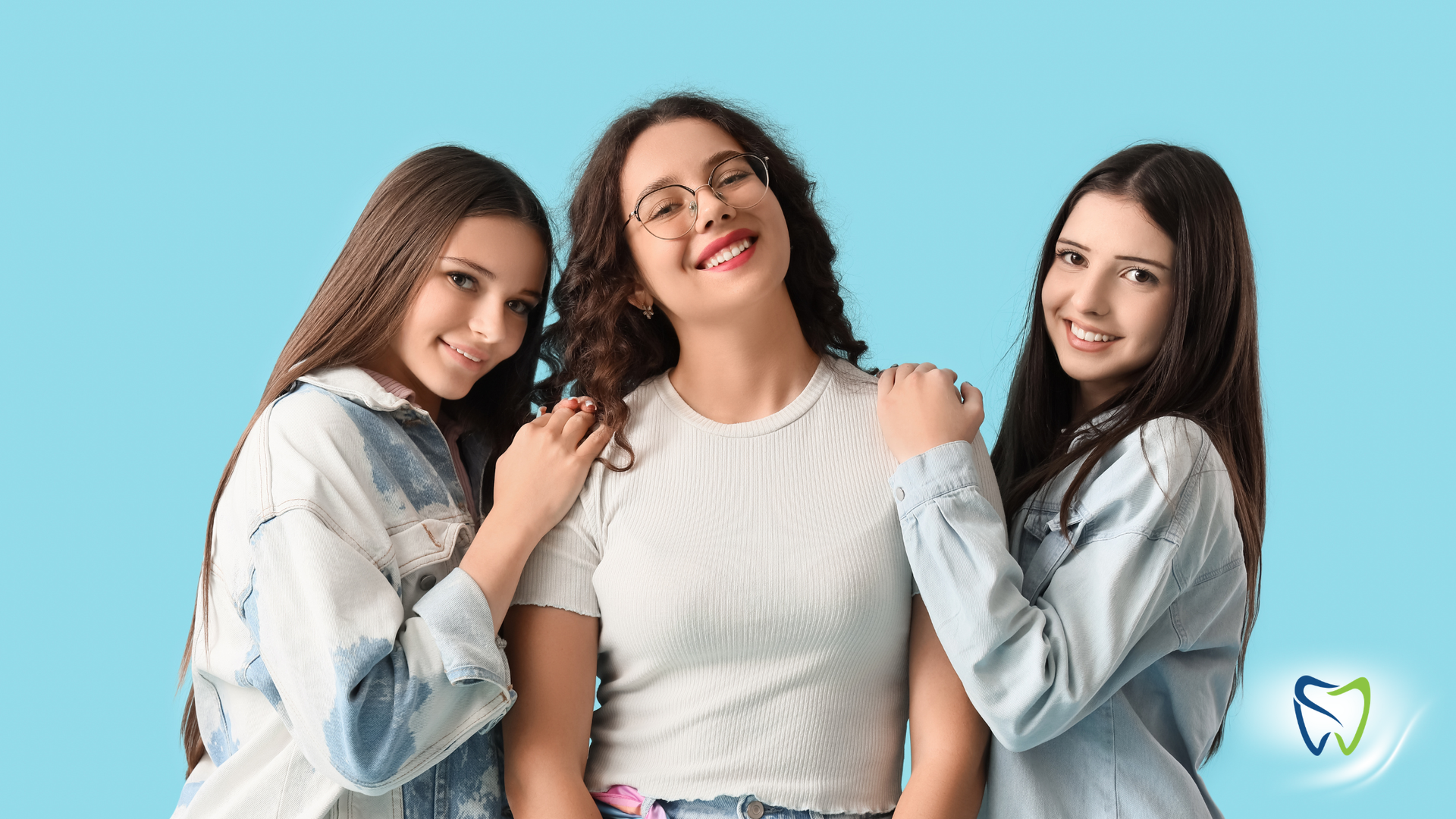 Four smiling people huddle together under a blue sky, arms around each other, looking down.