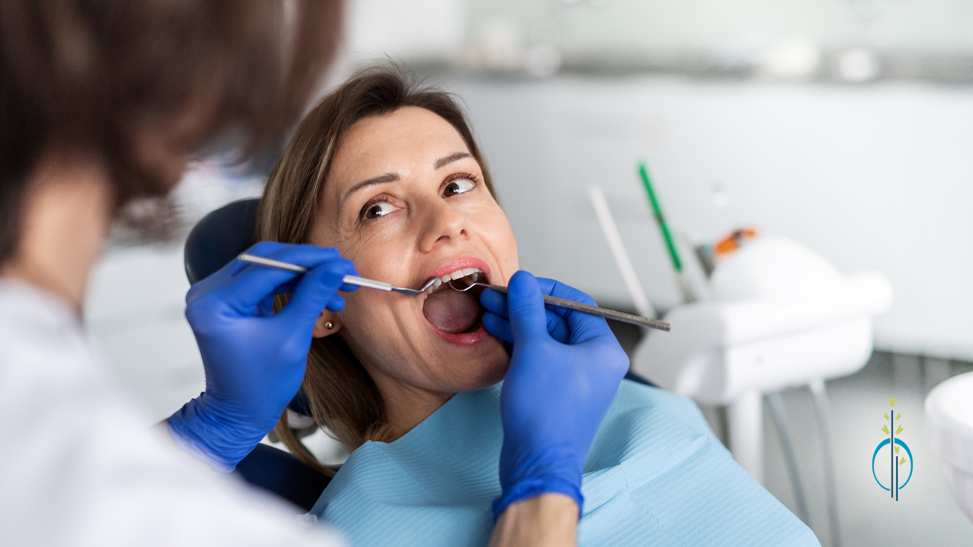 A woman is sitting in a dental chair getting her teeth examined by a dentist.