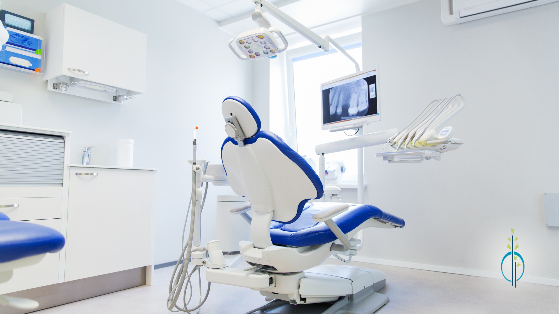 An empty dental office with a blue and white dental chair.