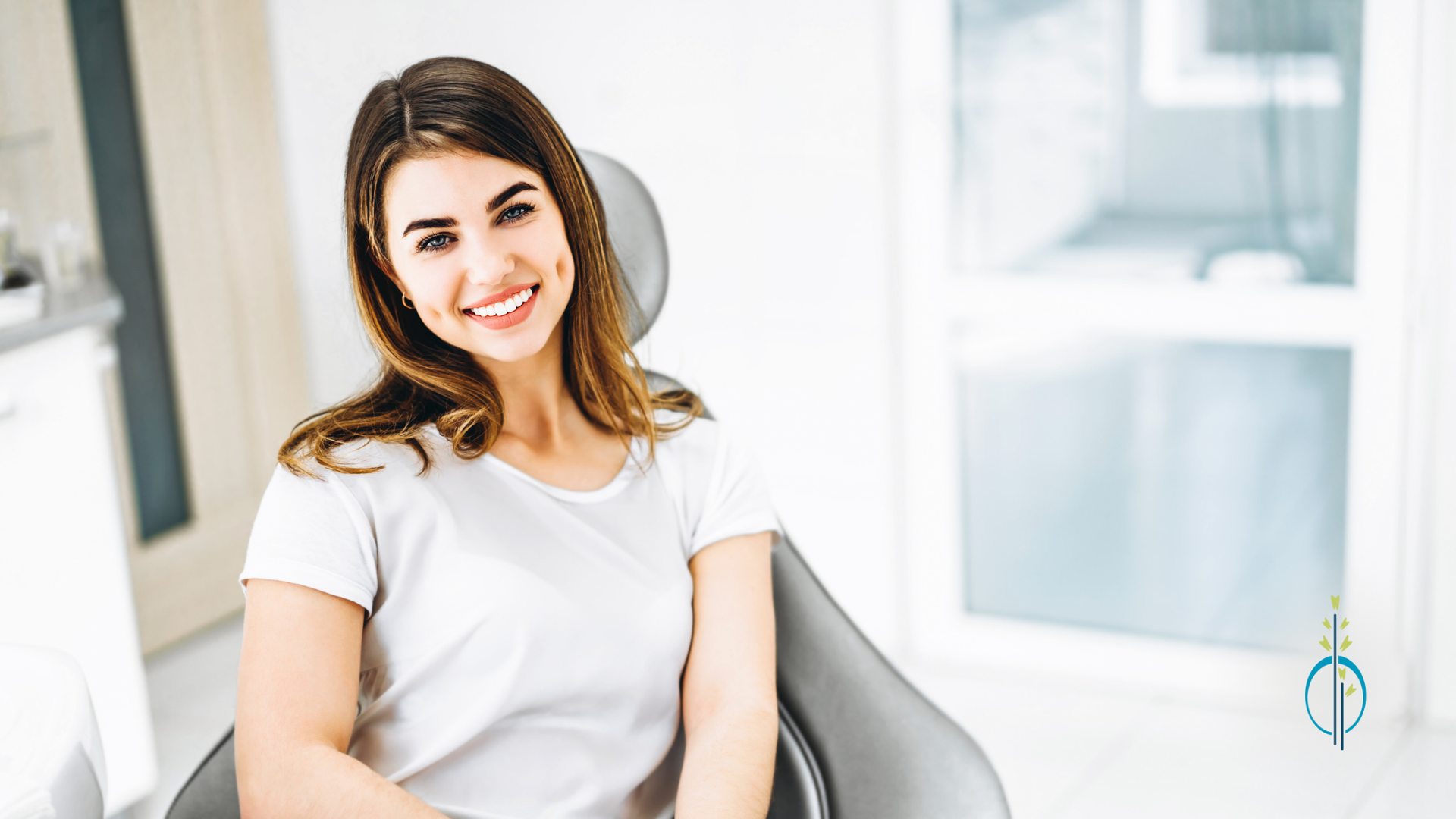 A woman is sitting in a dental chair and smiling.