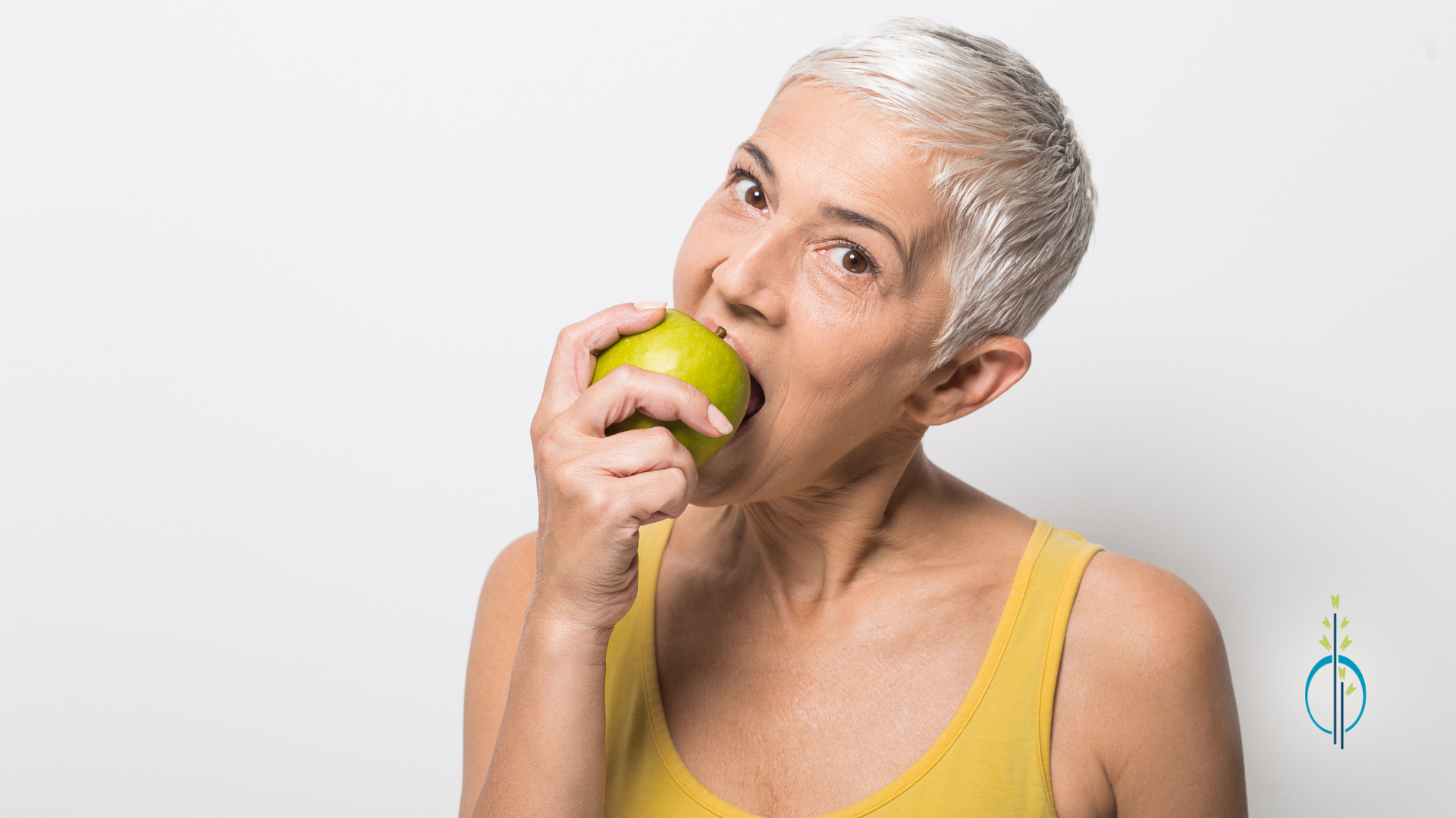 An older woman is biting into a green apple.