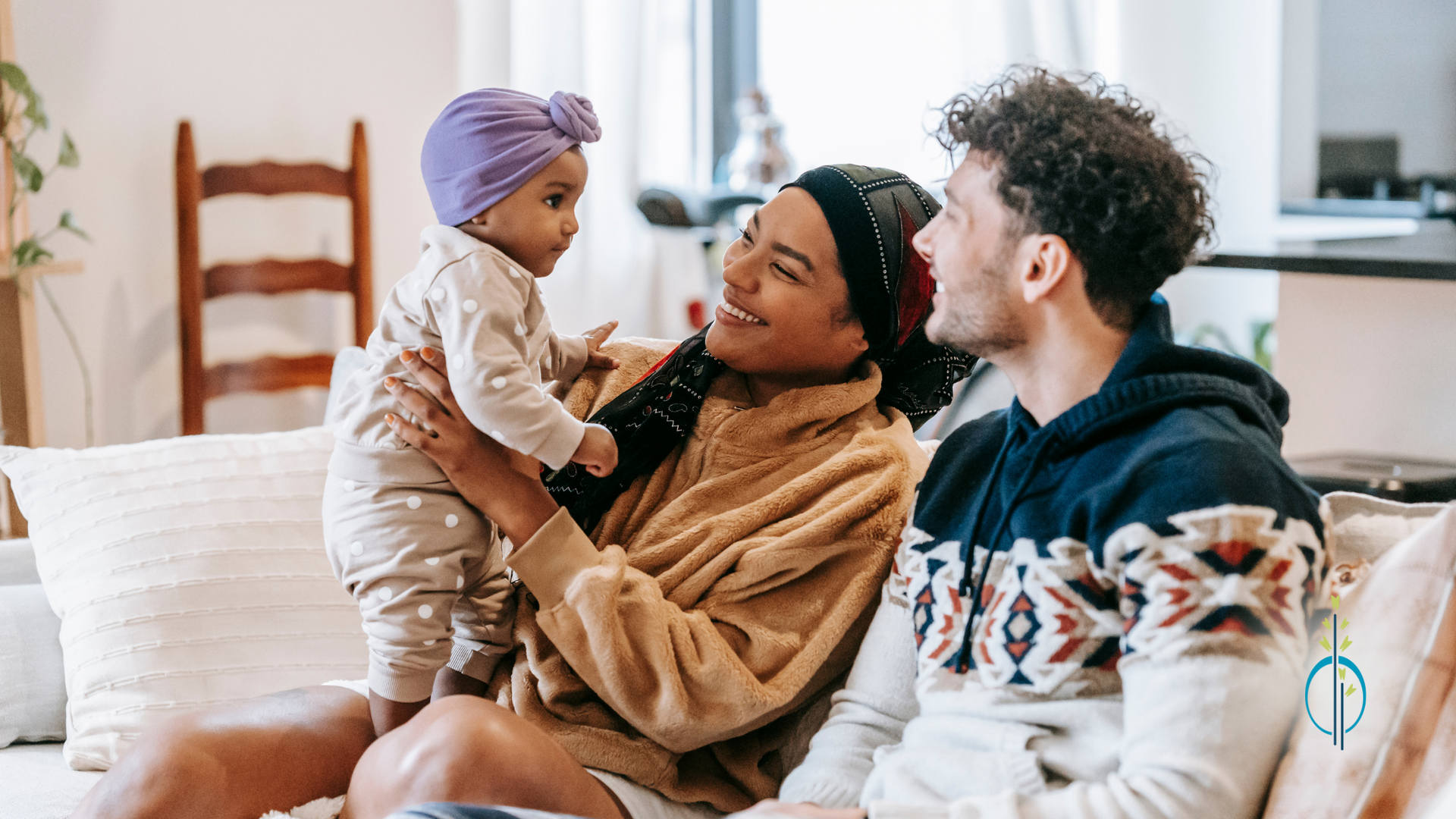 A man and woman are sitting on a couch holding a baby.