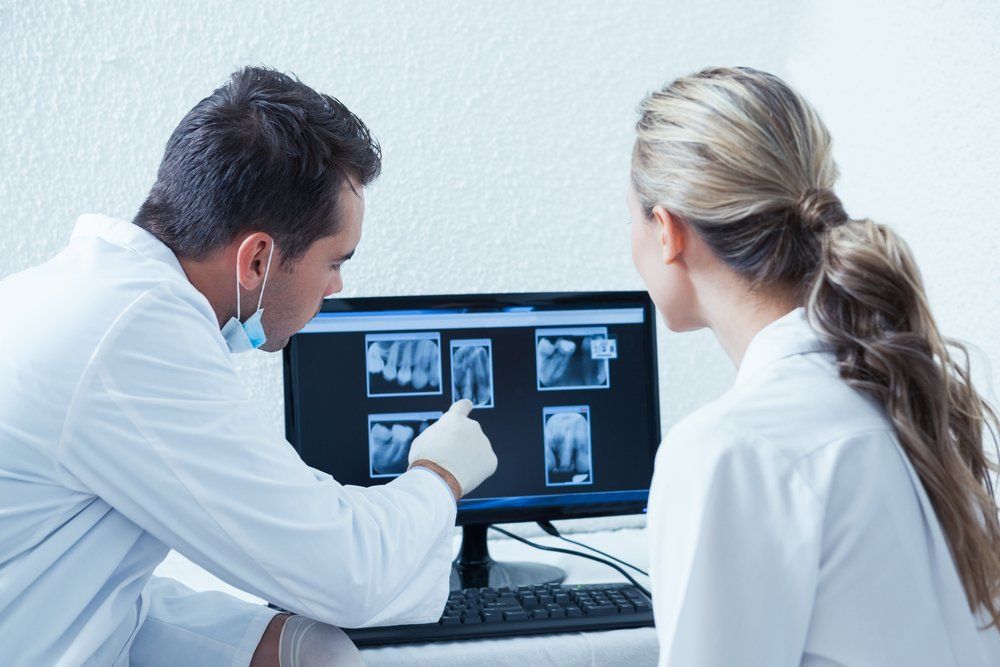 A man and a woman are looking at an x-ray on a computer screen.