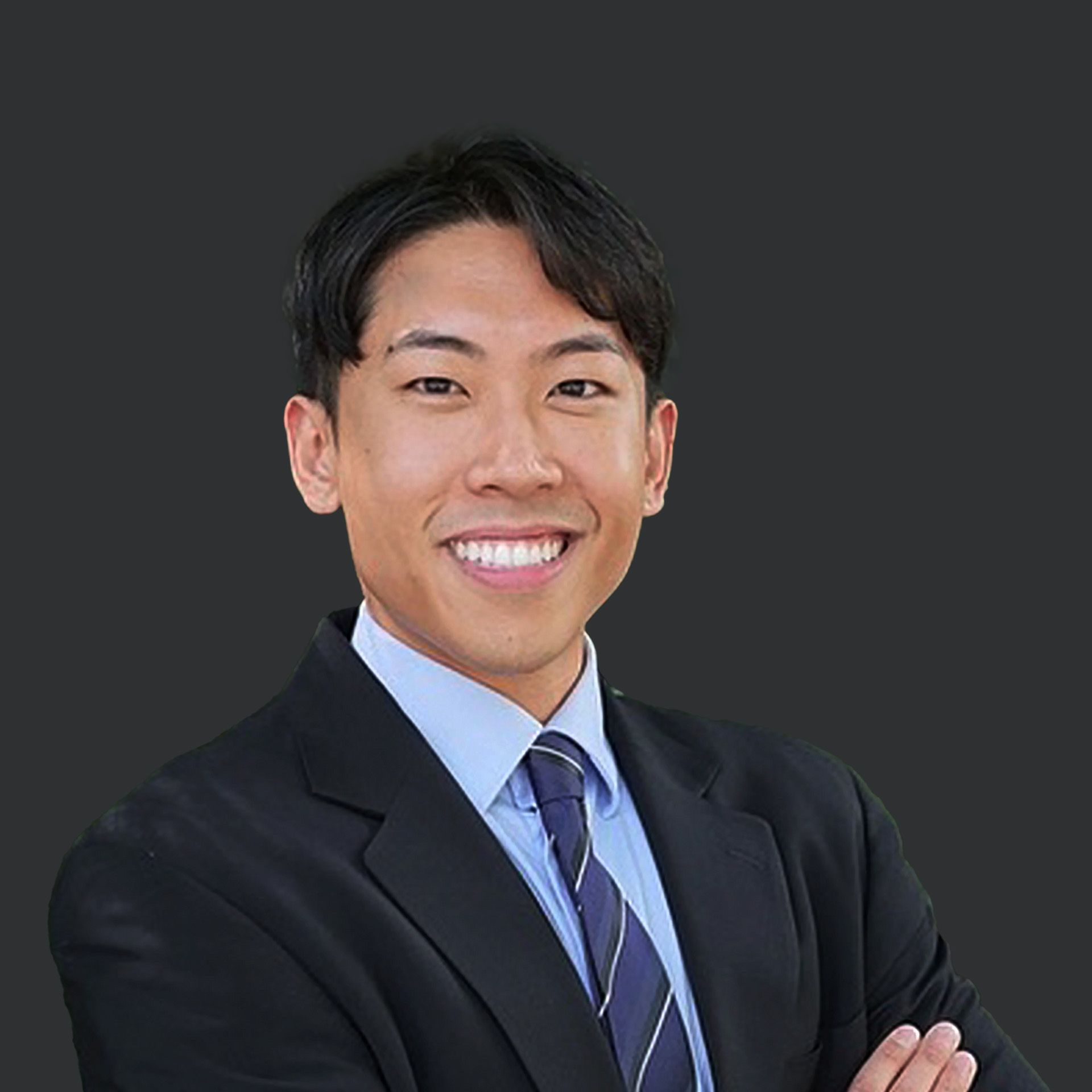 A man in a suit and tie is smiling with his arms crossed.