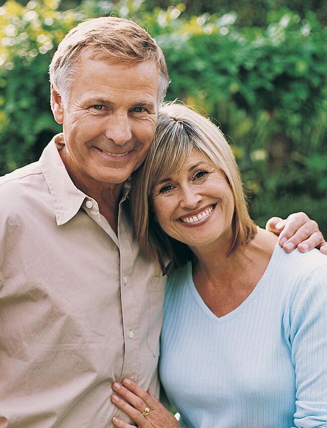 A man and woman are posing for a picture and smiling for the camera