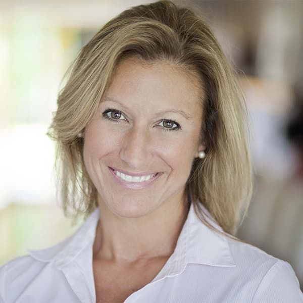 A woman in a white shirt is smiling for the camera.
