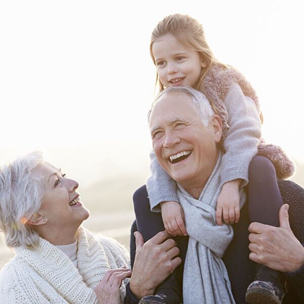 A man is carrying a little girl on his shoulders.
