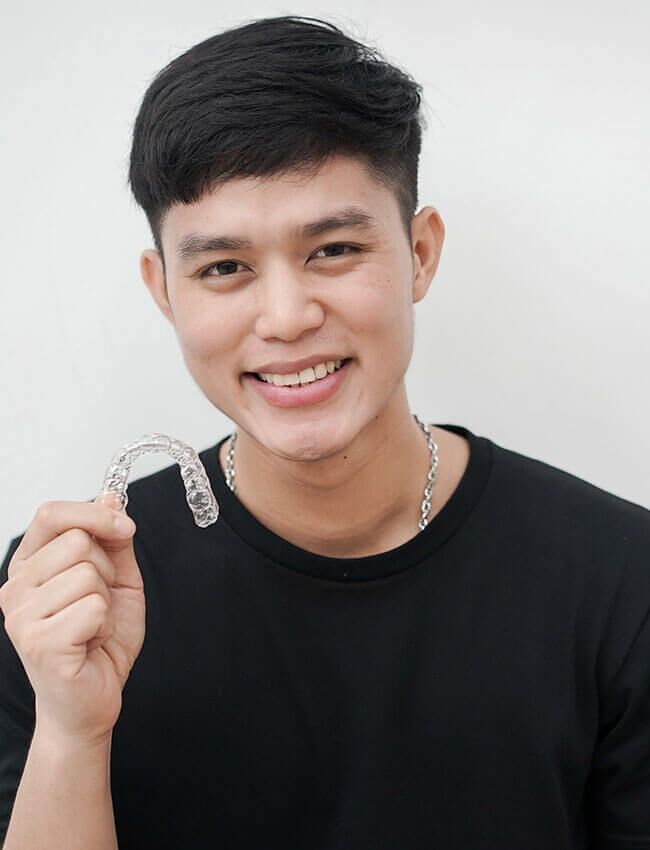 A man in a black shirt is holding a clear brace in his hand.