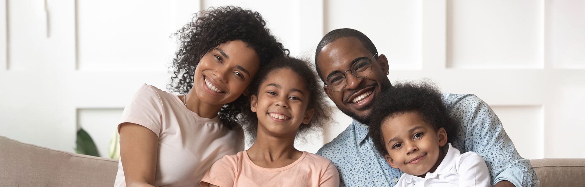 A family is posing for a picture while sitting on a couch.