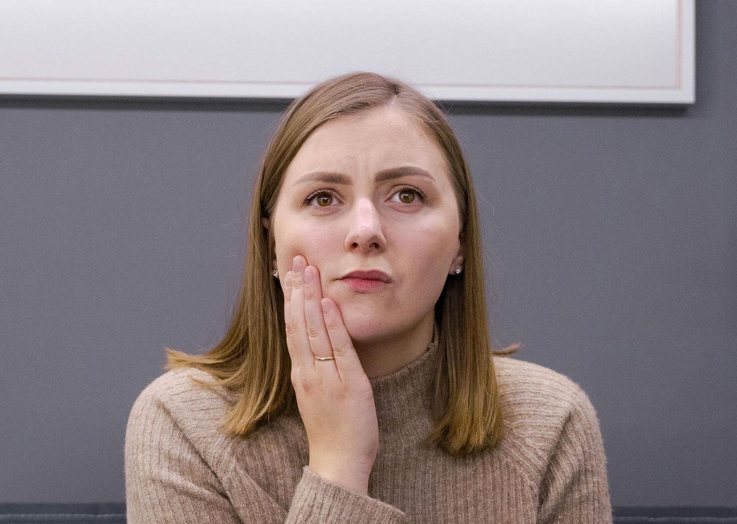 A woman is holding her face in pain because she has a toothache.