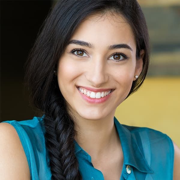 A woman with braided hair is smiling and wearing a blue shirt