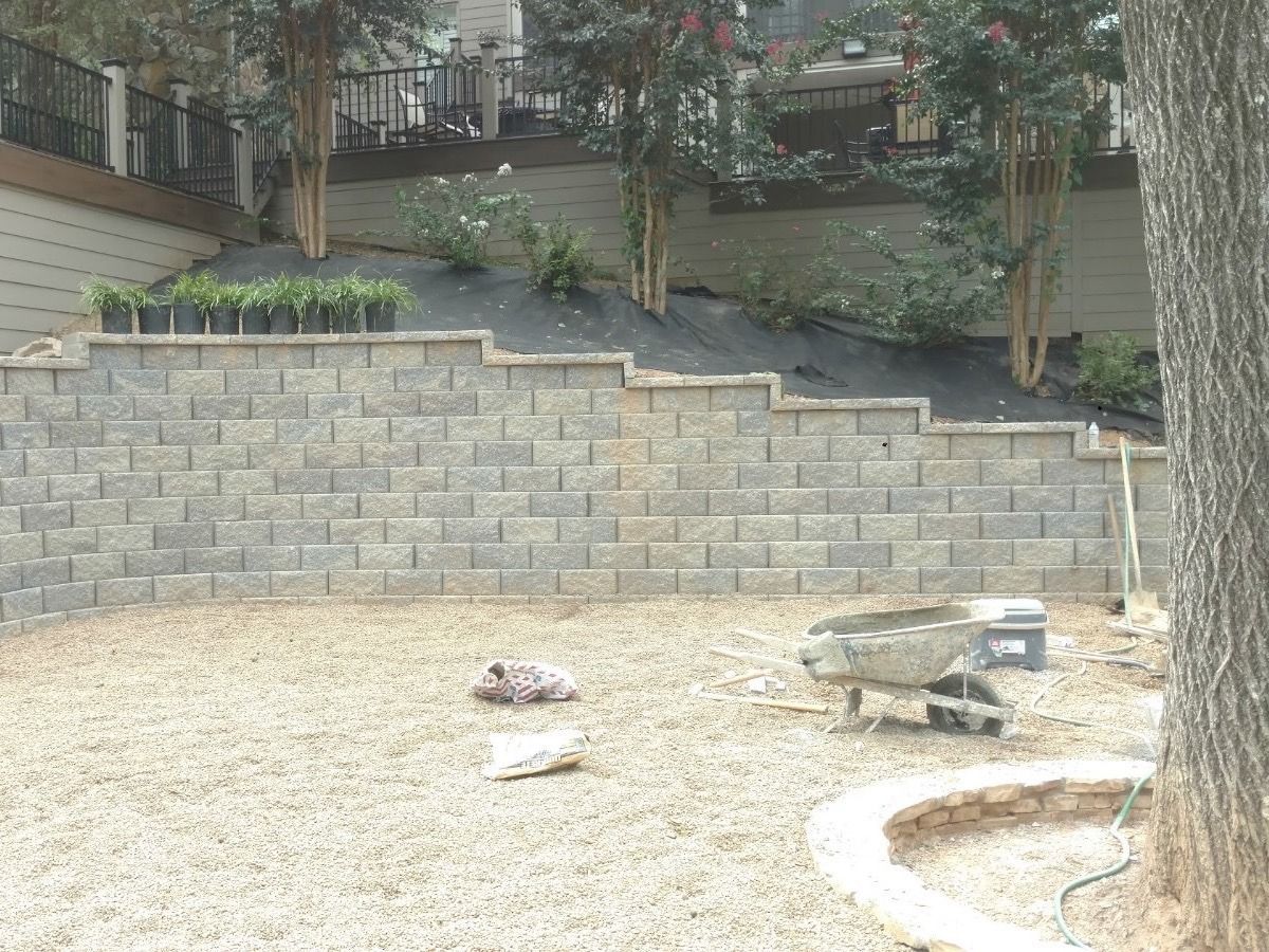 A wheelbarrow is sitting in the dirt in front of a brick wall