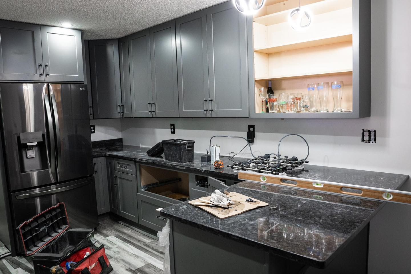 A kitchen is being remodeled with gray cabinets and granite counter tops.