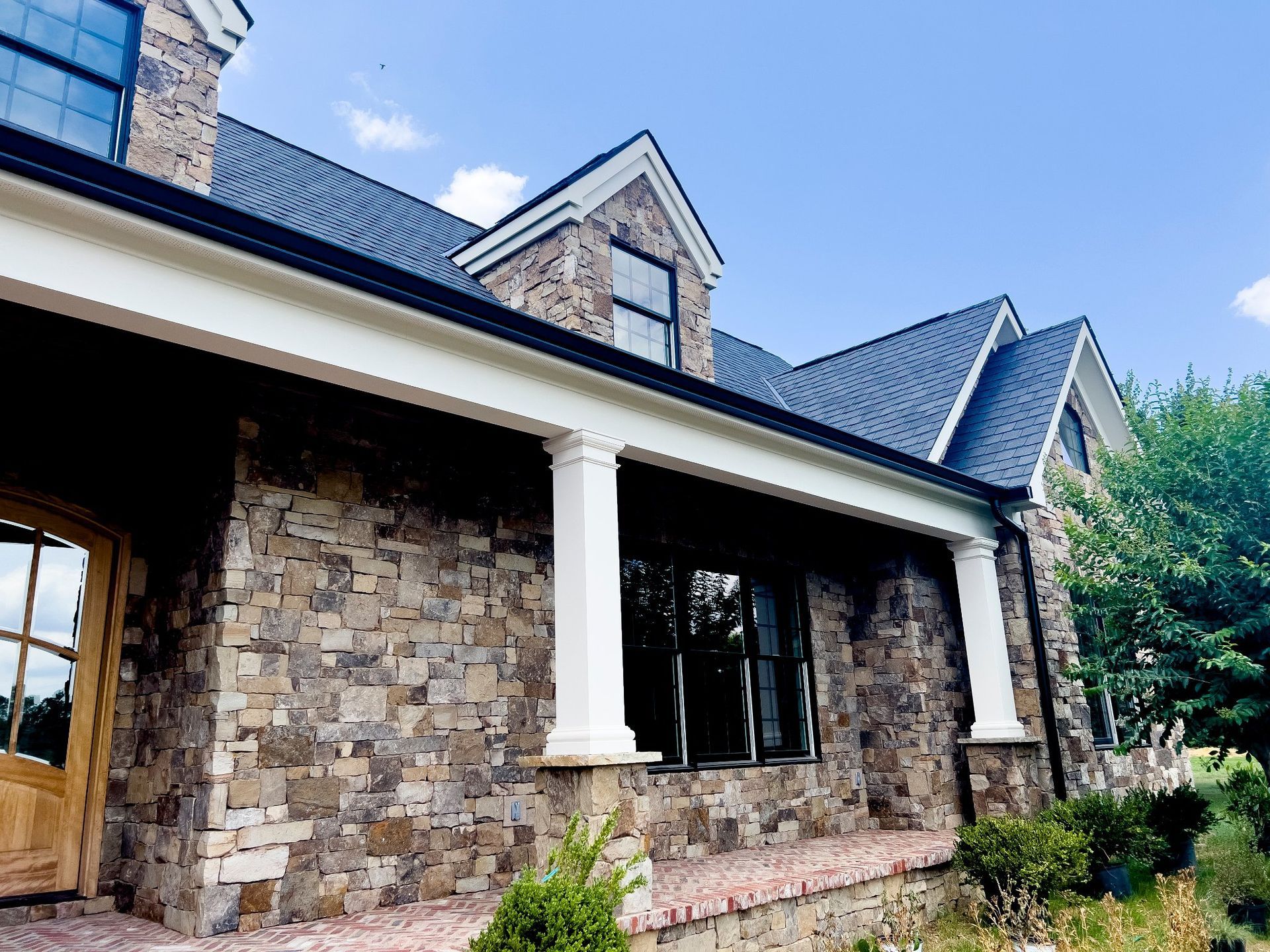 A large stone house with a porch and a gray roof.