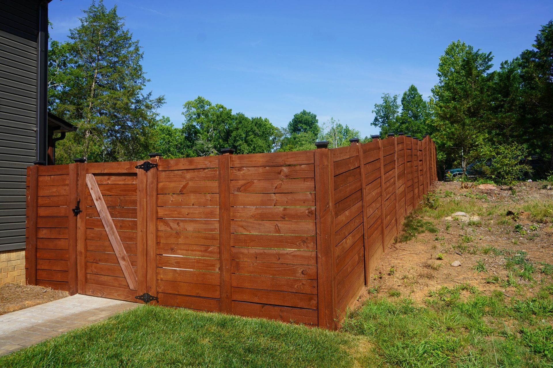 A wooden fence with a gate in the backyard of a house.