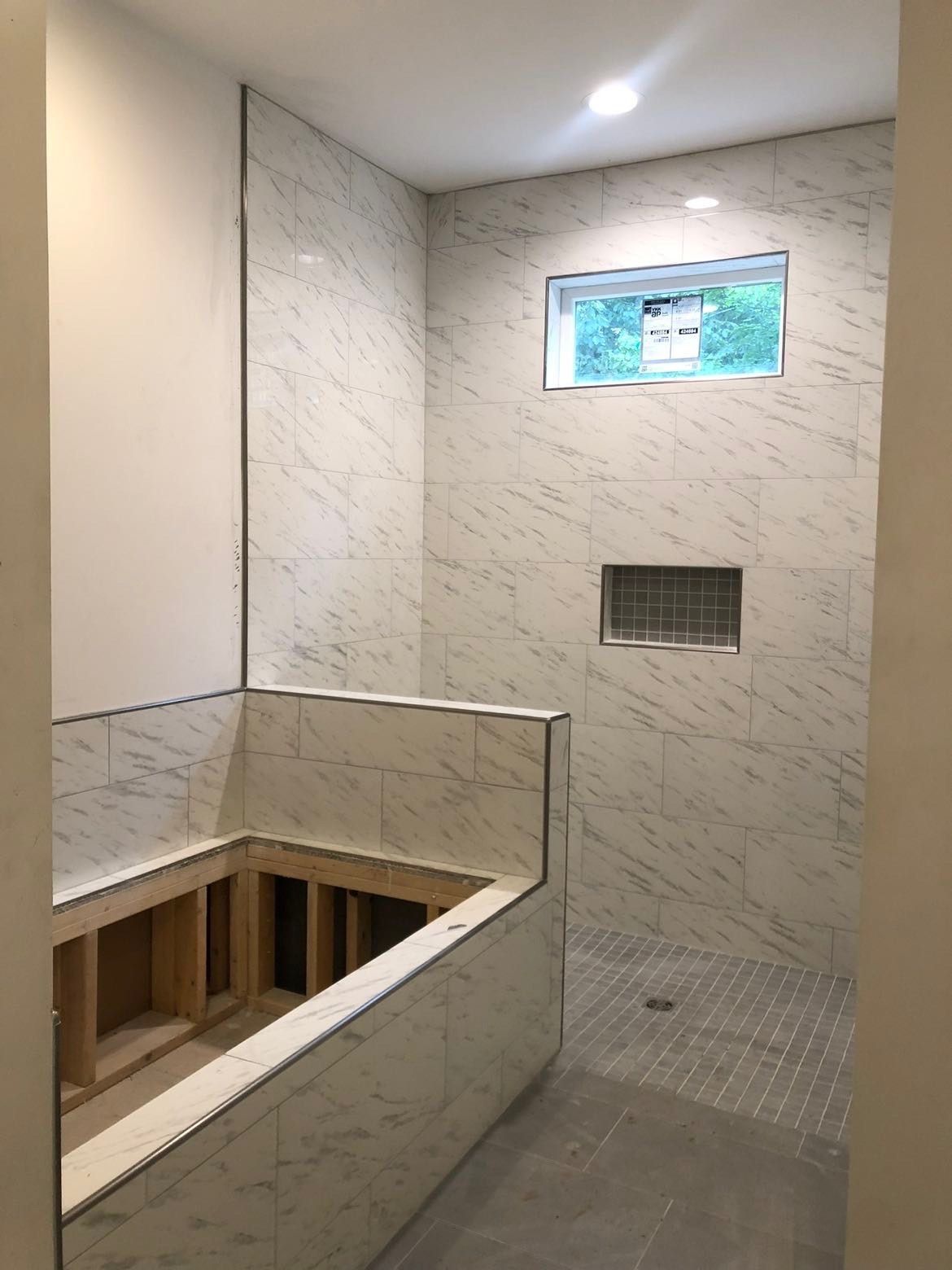 A bathroom with a walk in shower and a window.