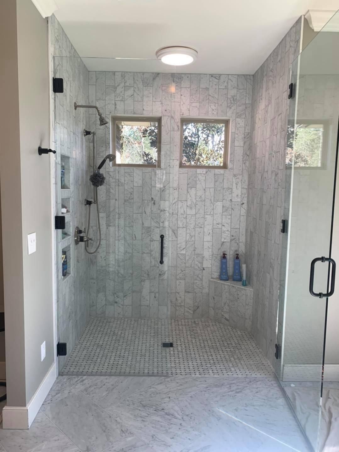 A bathroom with a walk in shower and a glass door.