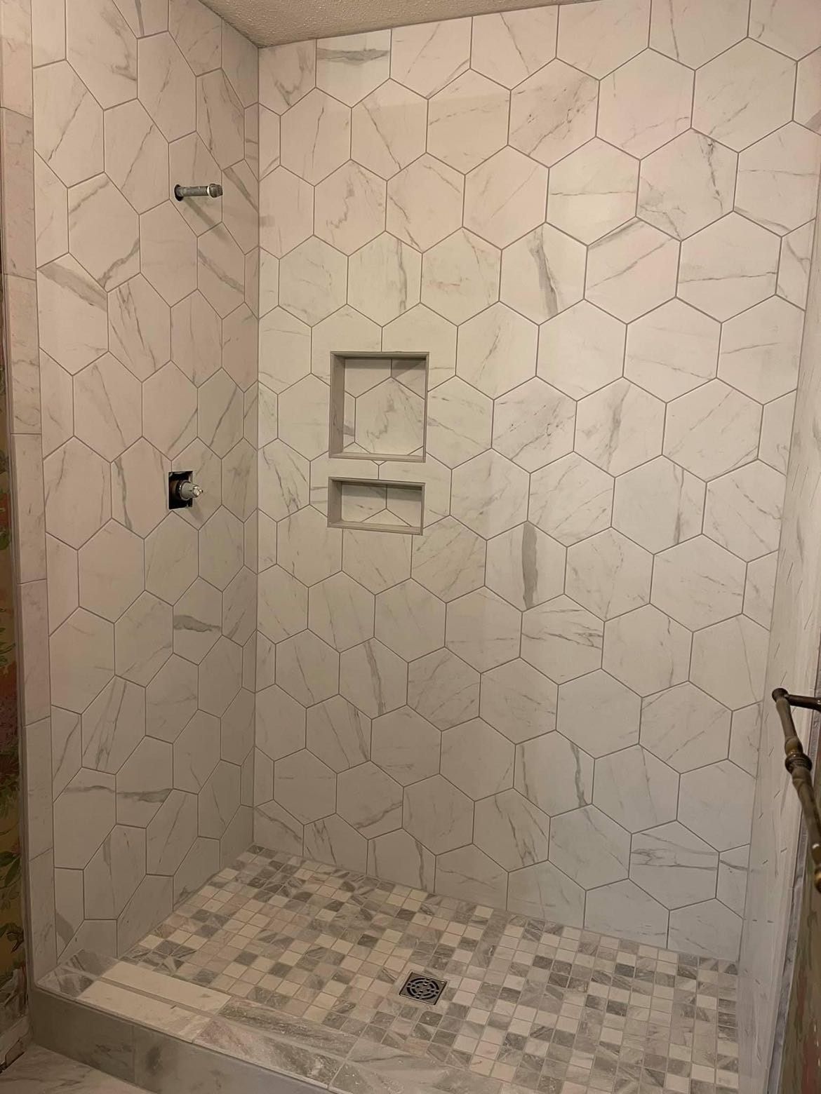 A shower stall with white tiles and a shower head.
