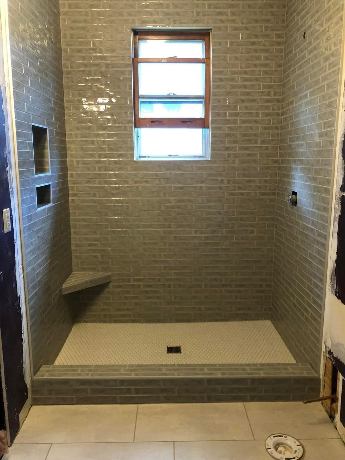 A bathroom with a walk in shower and a window.