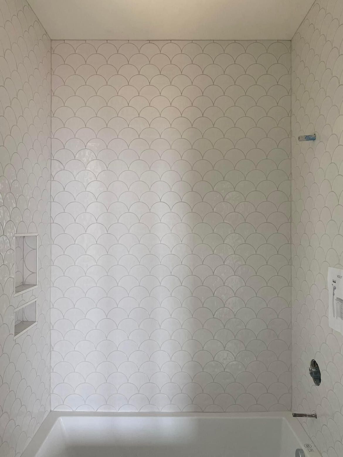 A bathroom with white tiles and a bathtub.