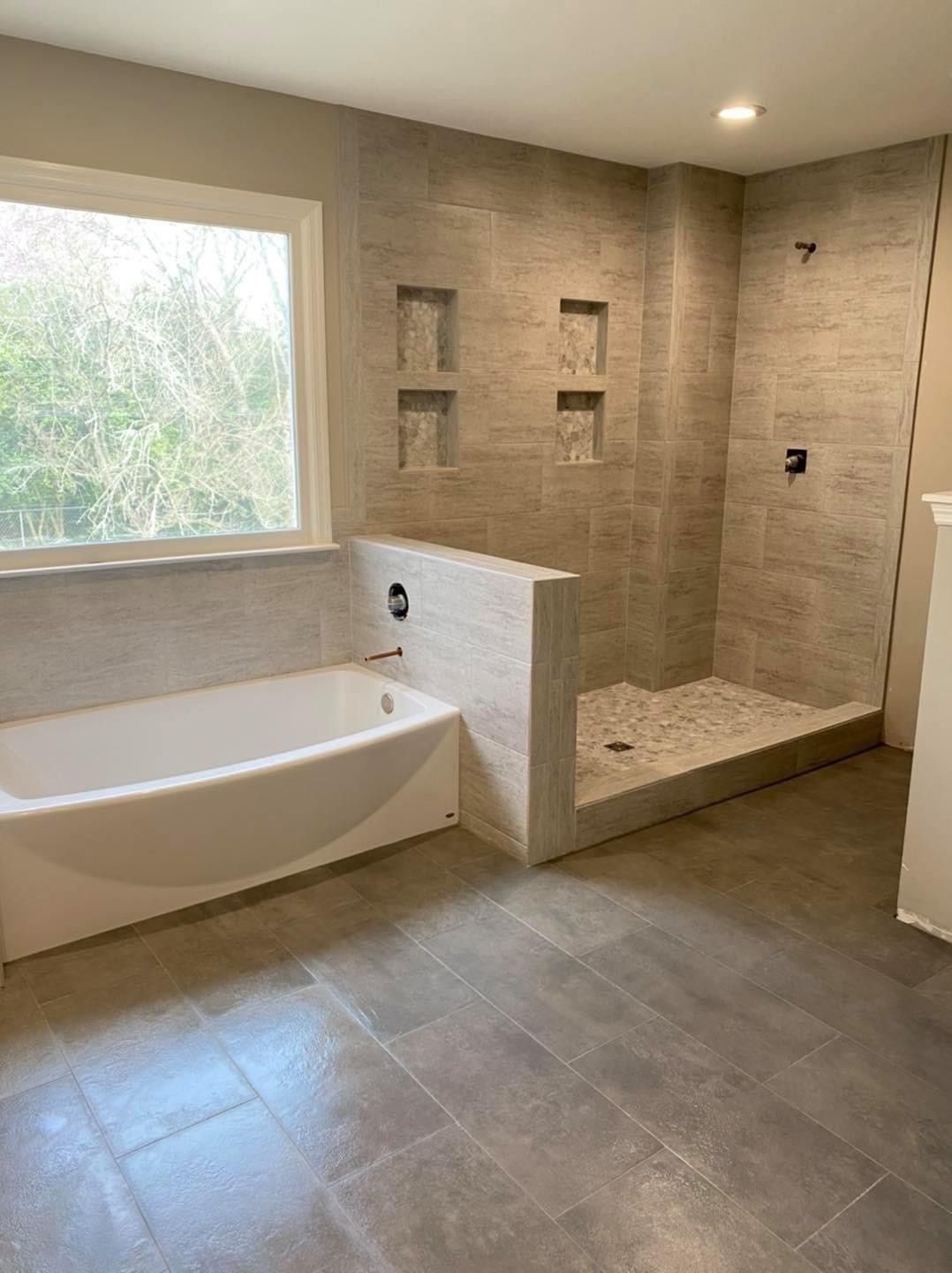 A bathroom with a walk in shower and a television on the wall.